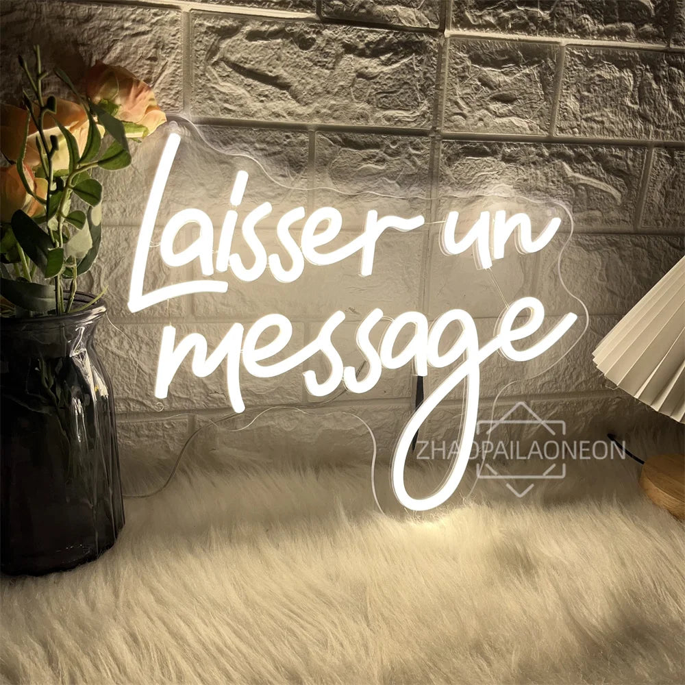 A glowing white neon sign spelling out 'Laisser un message' is displayed on a textured wall above a fluffy white rug.