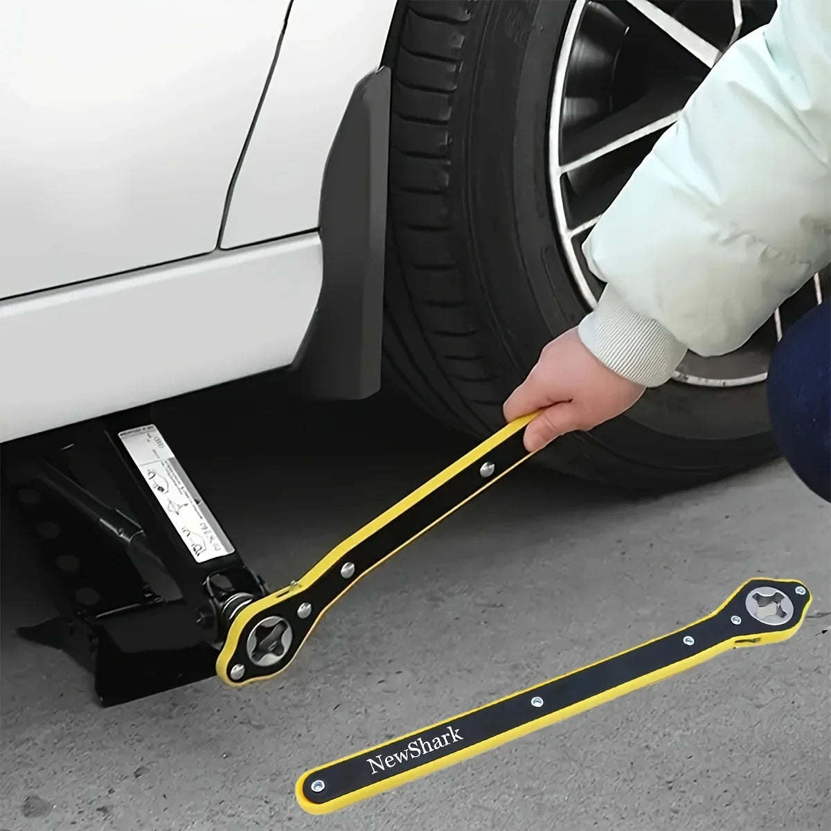 Eine Hand benutzt einen gelben NewShark-Hebemechanismus zum Reifenreparatur an einem Auto-Rad.