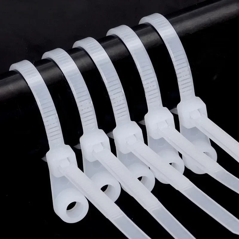 A row of clear reusable nylon cable ties with screw holes arranged horizontally.