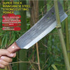 A hand holds a super-thick manganese steel knife with a wooden handle, shown against a blurred green outdoor background.