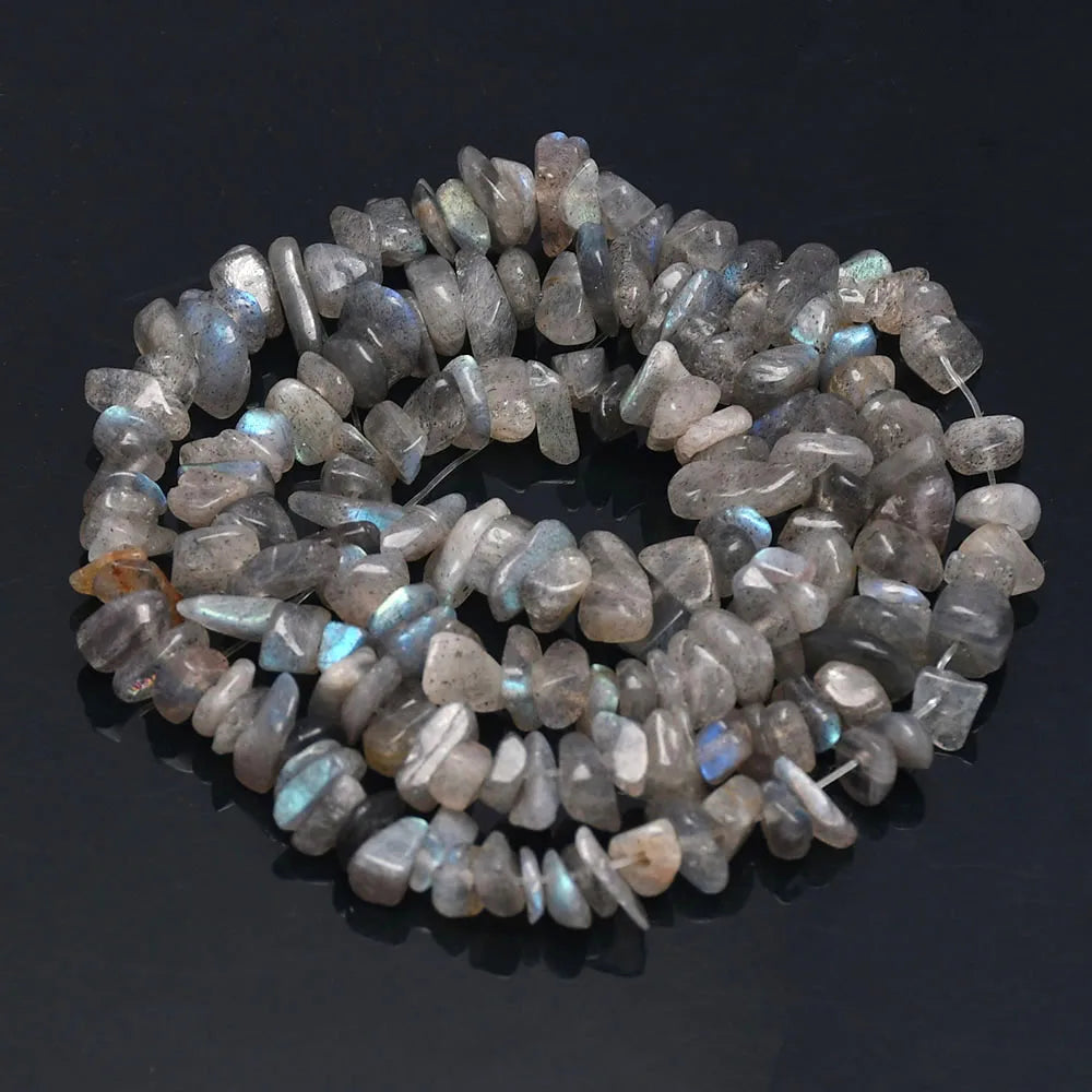 A circular arrangement of tumbled, translucent gray and blue-tinged agate beads for jewelry making.