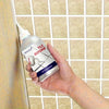 يد تمسك بقلم إصلاح مادة الجراوت لـ Tile Reform مقابل خلفية حائط مبلط.