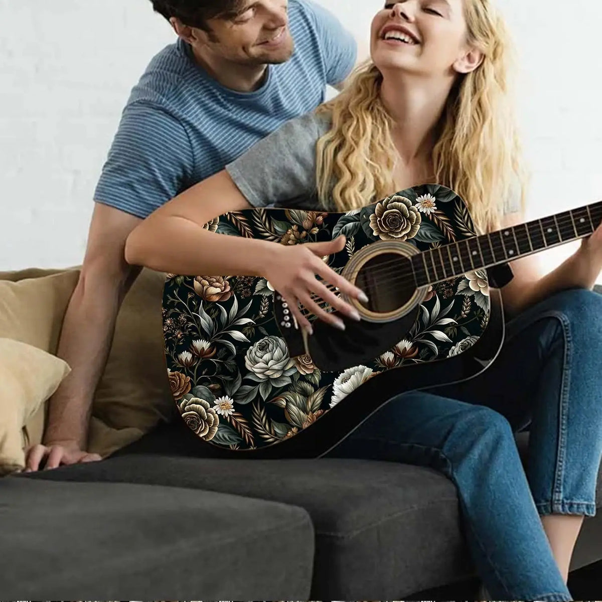 A smiling couple playing an acoustic guitar together in a cozy indoor setting.