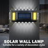 A close-up view of a solar wall lamp with a rectangular panel and surrounding light elements mounted on a gray wall.