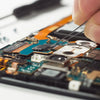 A hand uses precision tweezers to manipulate components on a circuit board.