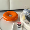 Orangene dekorative LED-Wandleuchte in Donutform auf einem weißen Tablett.