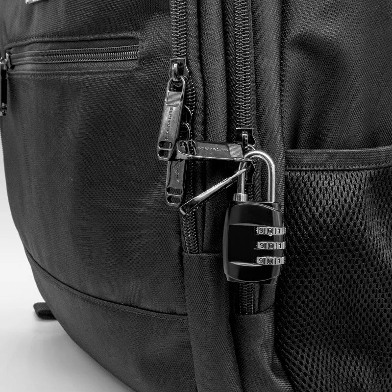 Close-up of a black luggage lock and combination safe attached to a black nylon backpack.