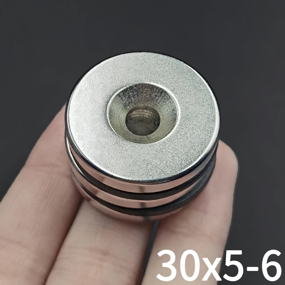 A hand holds a precision disc counter with a round, silver-colored magnetic head.