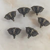 A collection of vintage bee cabinet handles or retro bar drawer pulls, featuring metallic, winged designs.