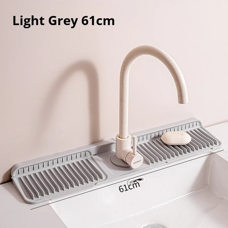 A light grey kitchen faucet mounted on a silicone sink splash mat above a white sink.