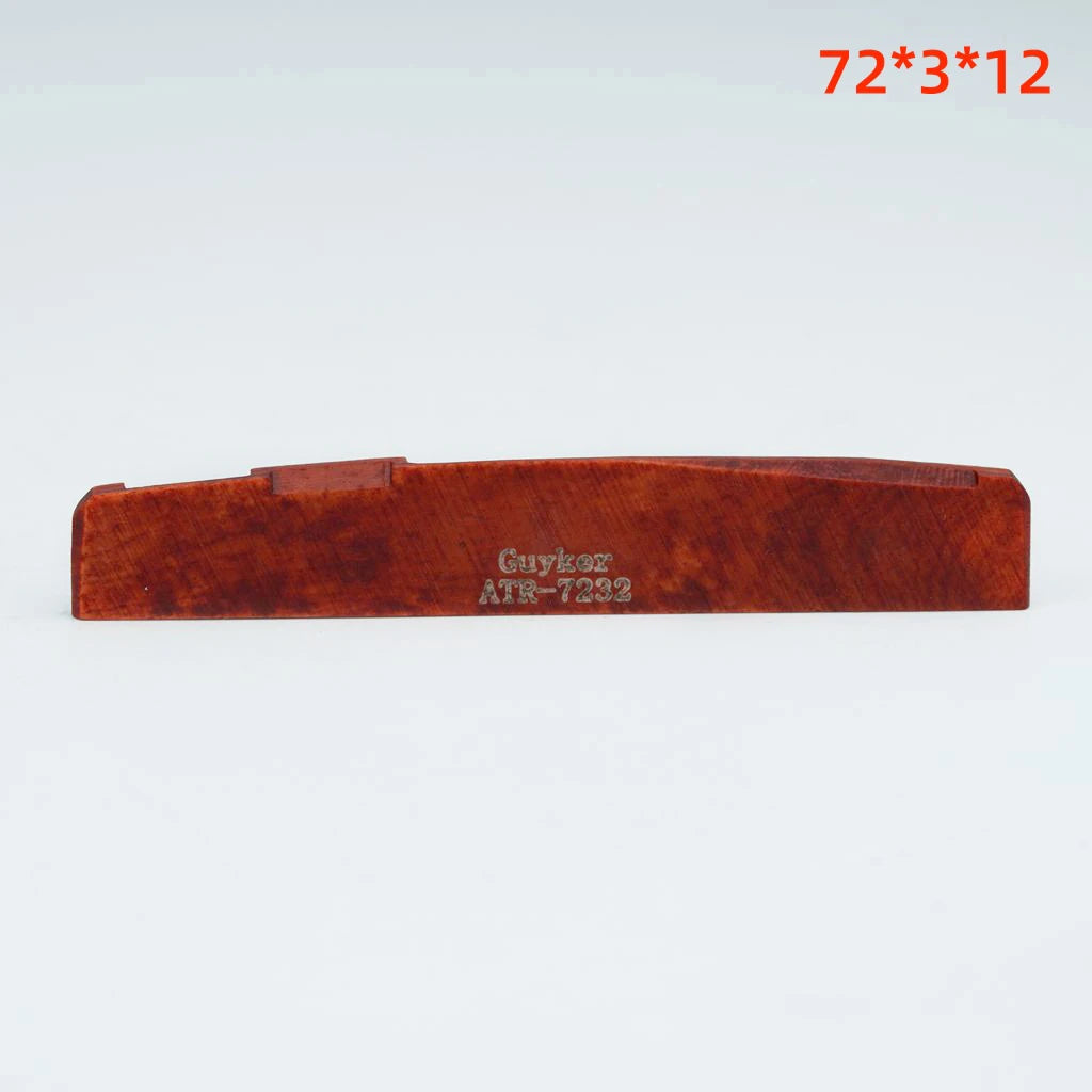 A wooden acoustic guitar bone bridge saddle with the marking Guykoz ATR-7232
