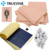 A set of professional tattoo practice skin and transfer kits including a detailed floral design and a rolled blue sheet.