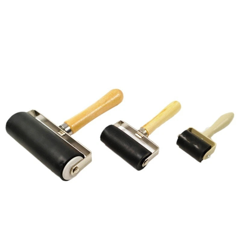 A professional set of rubber roller printing tools with black rollers and wooden handles.