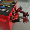 A red toolbox holds various tools, including pliers and a cordless drill, on a gray workbench.