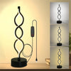 A black desk lamp shaped like a spiraling seaweed illuminates a workspace.