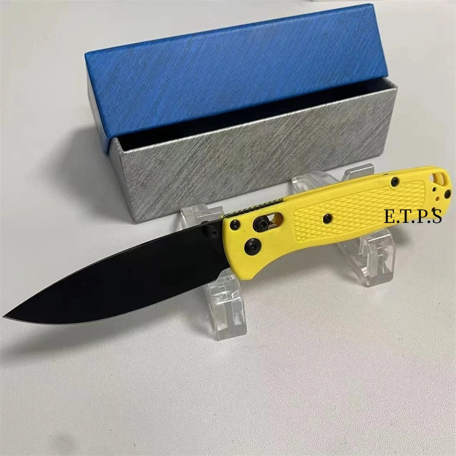 Un couteau de poche pliable jaune avec une lame noire est exposé à côté de sa boîte d'emballage argentée et bleue.