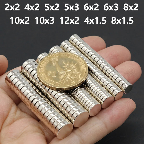A hand holds a collection of various sized and shaped fridge magnets with silver-colored metal discs.