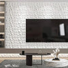 A modern living room featuring a large television mounted on a white diamond pattern wall panel and wooden furniture.
