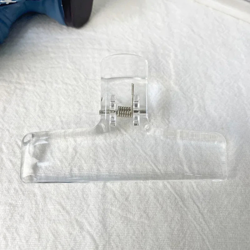 Transparente Acryl-Federklammern auf einem weißen Tuch.