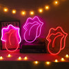 Neon pink heart lip light decoration glowing on a dark background with string lights.