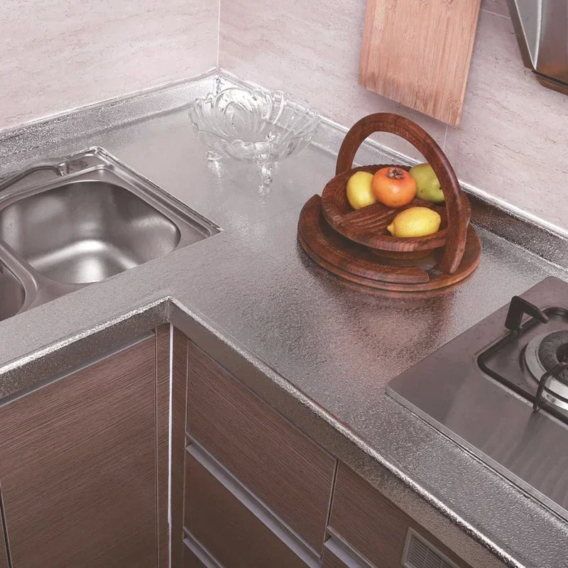 Un comptoir de cuisine avec un évier en acier inoxydable, des bols en bois avec des fruits et une zone de cuisinière.