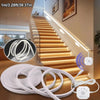 White LED light strip with a motion sensor is installed along a wooden staircase, creating a neon effect.