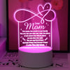 A glowing pink acrylic sign shaped like a heart with a handwritten message for Mom on a white base.