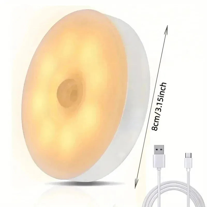 A round, white automatic motion sensor night light with a visible cord and power plug.
