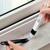 A hand is using a white and black 2-piece window track cleaning brush set to clean a window frame.