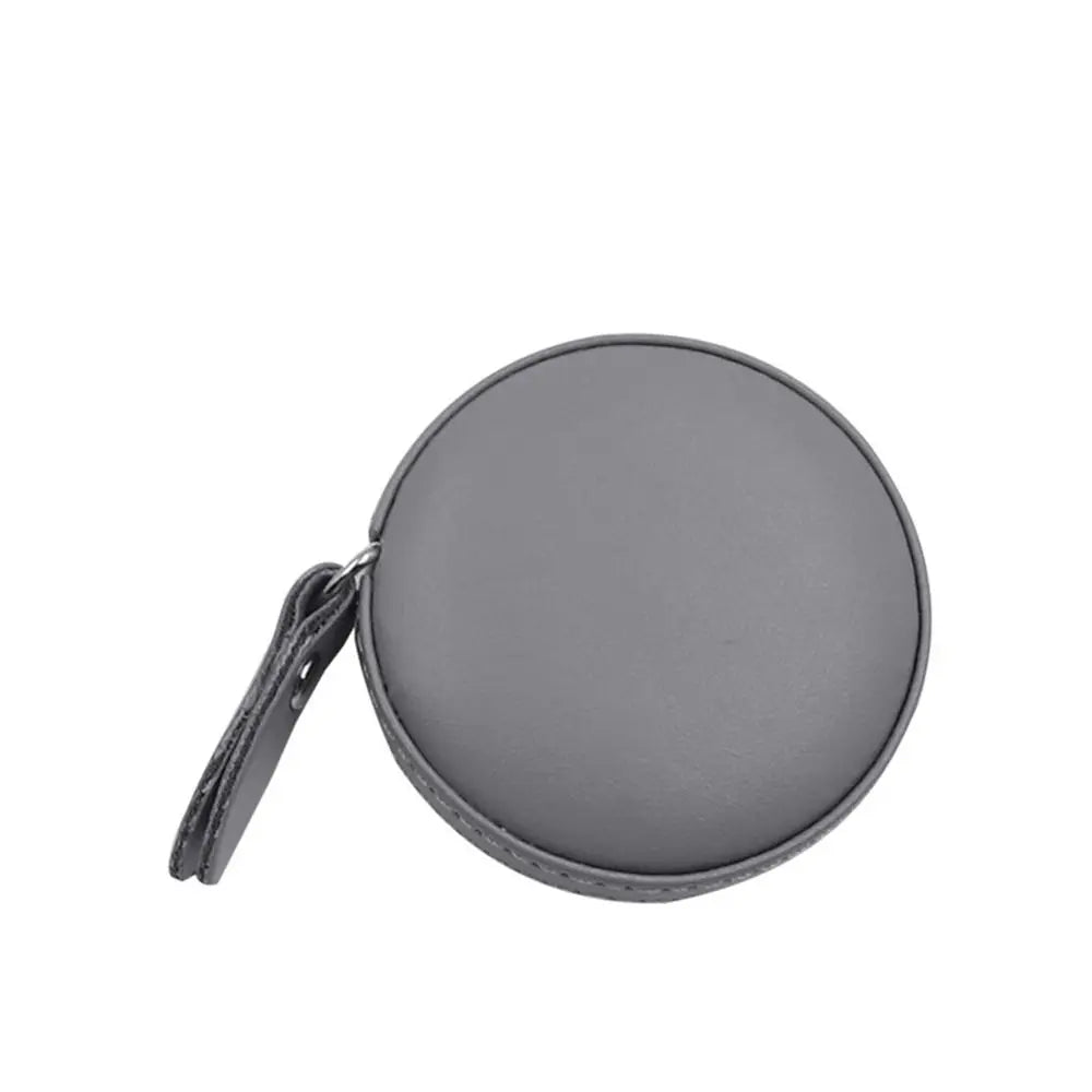 A gray retractable dual scale measuring tape with a leather strap.