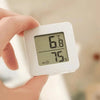 A hand holds a white compact digital temperature and humidity gauge displaying 66.8 degrees and 75 percent humidity.