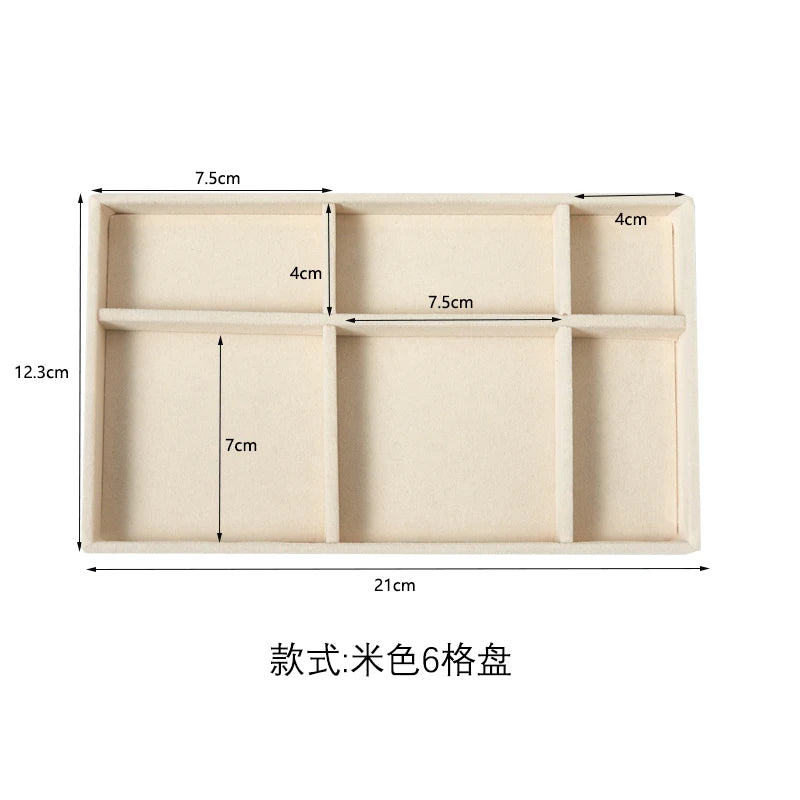A rectangular light beige plush velvet jewelry storage tray divided into six compartments.
