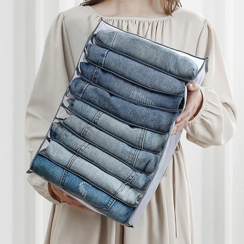 A hand holds a clear storage box filled with neatly folded denim fabric organizers.