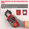 A hand holds a red non-contact AC voltage detection clamp meter displaying a weak signal and an orange backlight.