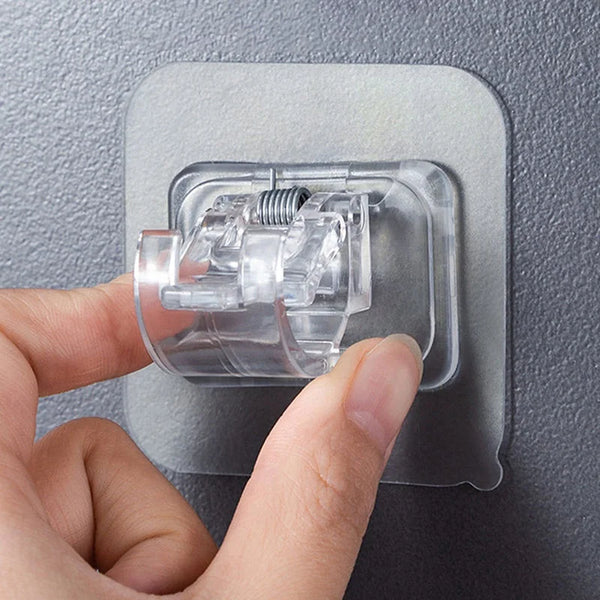 Une main installe un crochet de rail en plastique transparent auto-adhésif sur un mur gris.