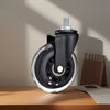 A close-up view of a black furniture caster wheel with a threaded metal pin, resting on a wooden surface.