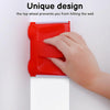 A hand is using a red precision paint edger tool to trim a corner on a white wall.