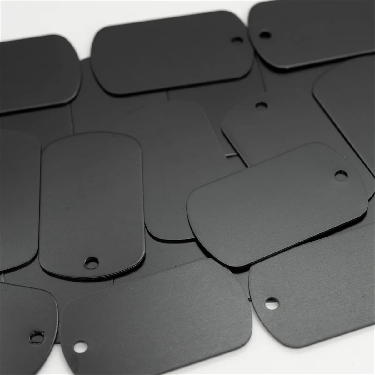 A collection of 50 black aluminum metal stamping tags for crafts and keychains.