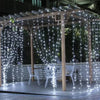 Holzpergola mit weißen LED-Lichterketten, die einen Außenbereich beleuchten.