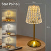 A tall, gold-toned desktop reading lamp with a textured glass shade sits on a wooden surface.