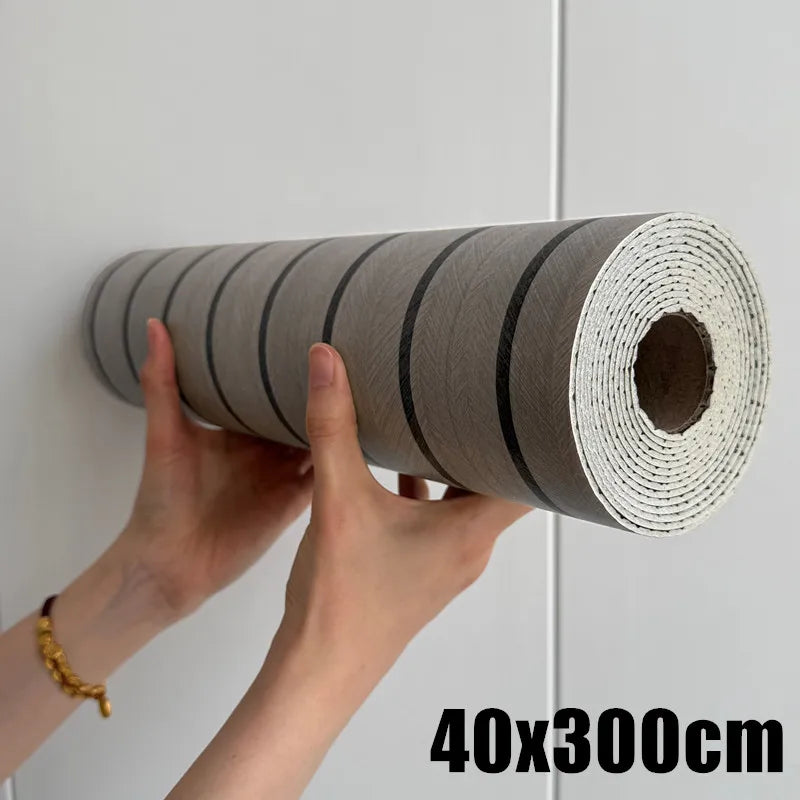 Roll of self-adhesive wood grain wall panels in gray and black, being held by a hand.