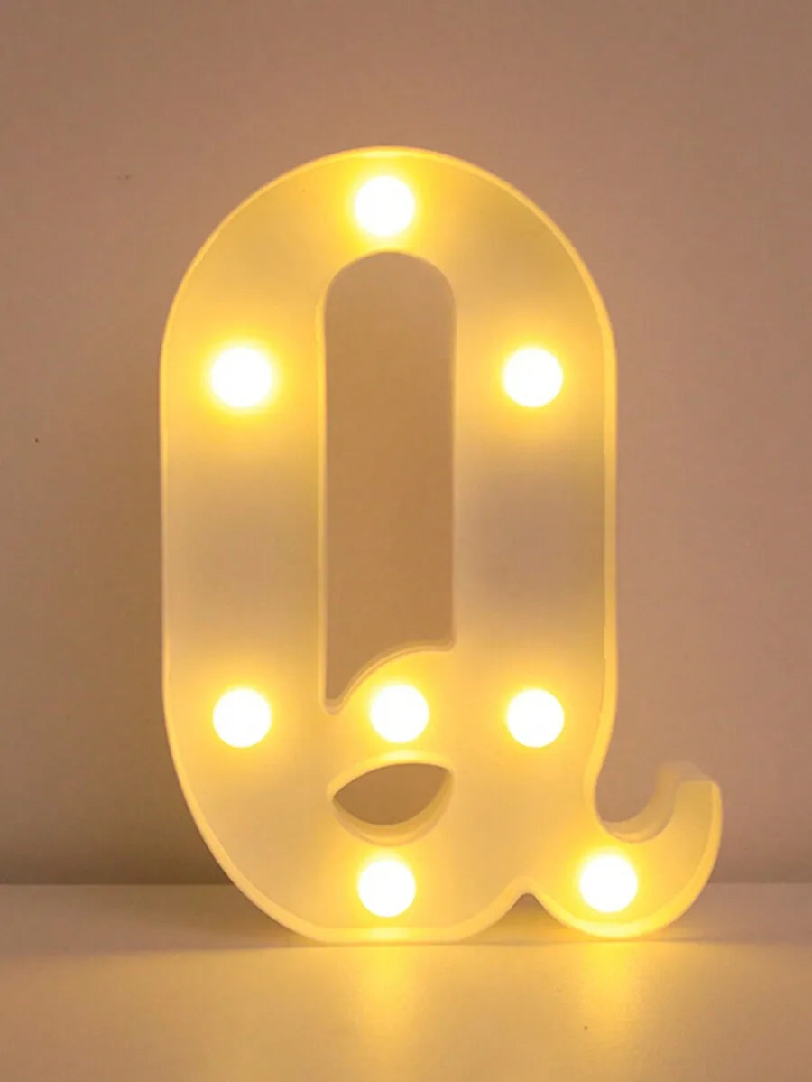 Luz nocturna con letra Q amarilla brillante LED iluminando la forma contra un fondo blanco.