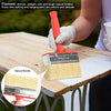A hand is using a natural bristle paint brush on a wooden table, demonstrating the bristles and handle.