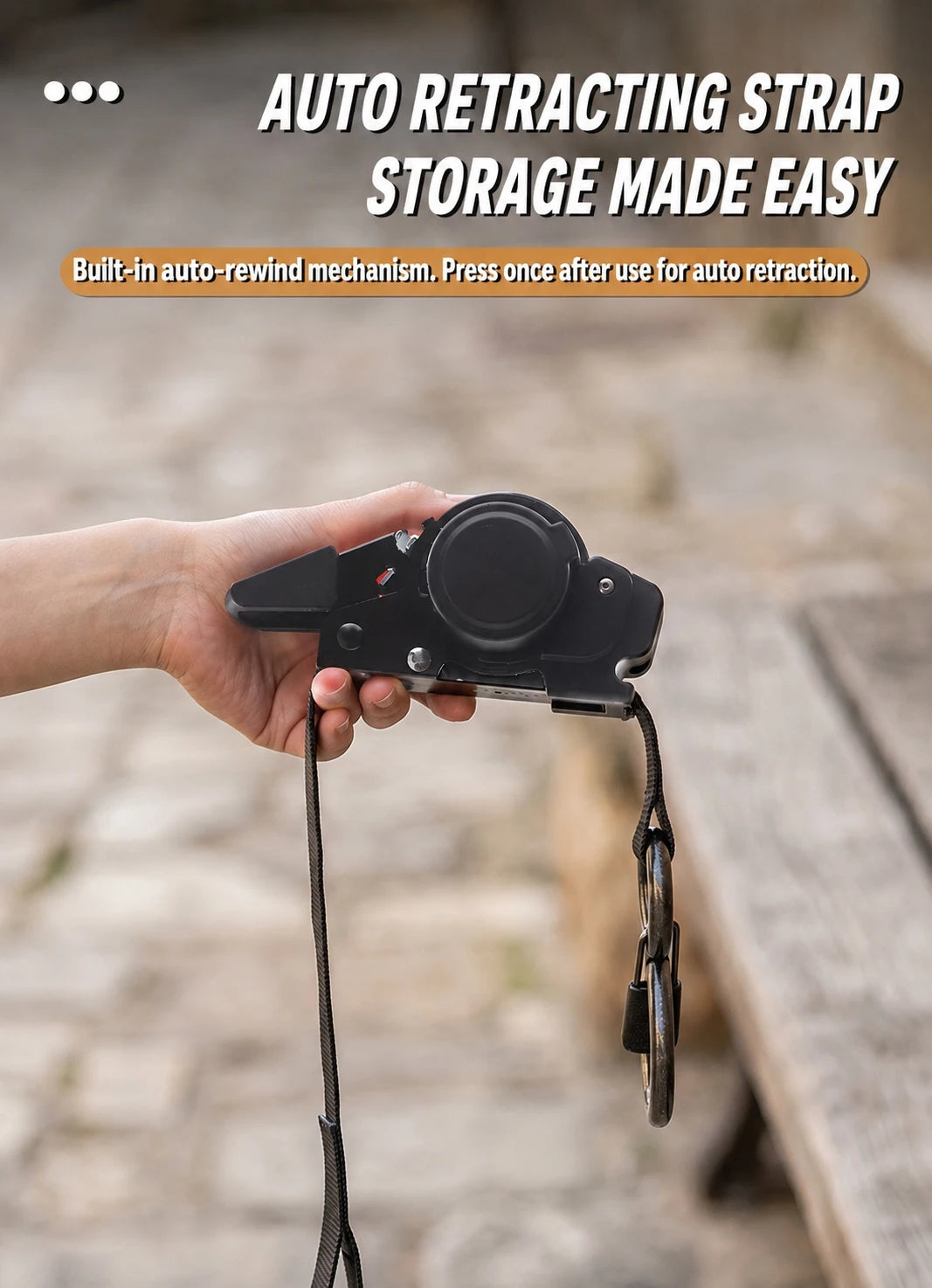 A hand holds a black auto retracting strap with a black cord attached, demonstrating its storage feature.