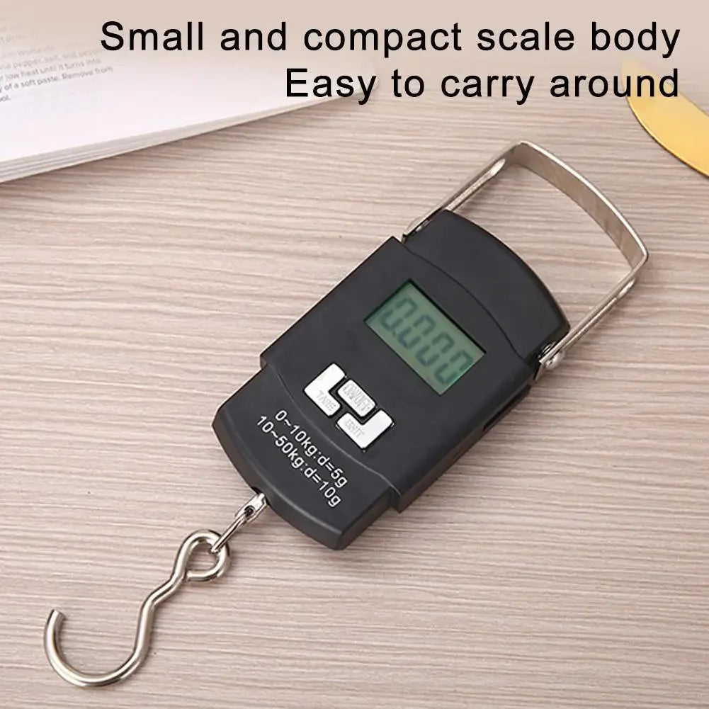 A black portable digital fishing scale with a metal hook is shown on a light wooden surface.