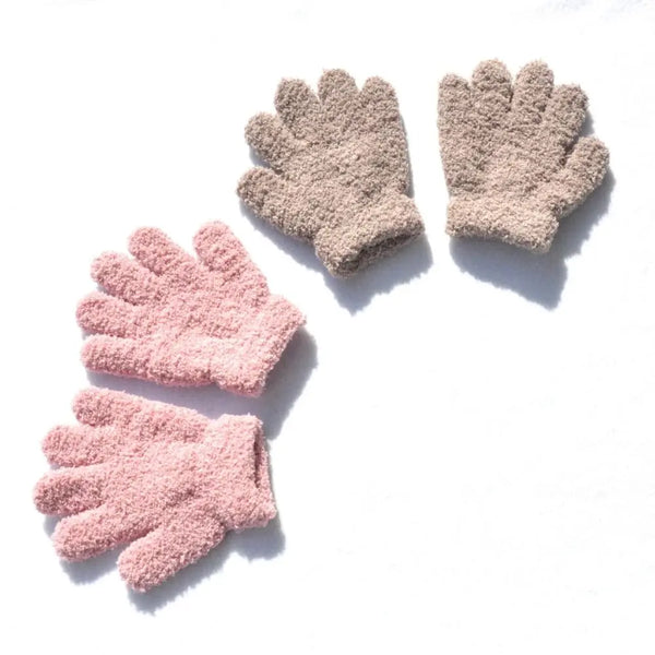 Ein Paar weiche Winterhandschuhe mit vollen Fingern für Kinder in hellrosa, vor weißem Hintergrund.