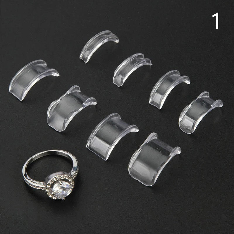 A set of clear plastic invisible ring sizing adjusters and a diamond ring are displayed on a black background.
