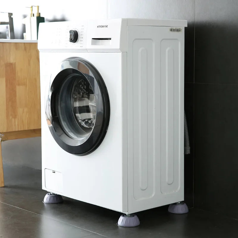 A white washing machine with anti-vibration silicone feet pads on a dark floor.