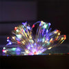 Un faisceau de guirlandes lumineuses en fil de cuivre, blanc chaud, ressemblant à une fleur ou une explosion.