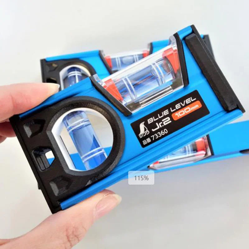 A hand holds a blue precision bubble level ruler set with a clear liquid and an orange-colored fluid inside.